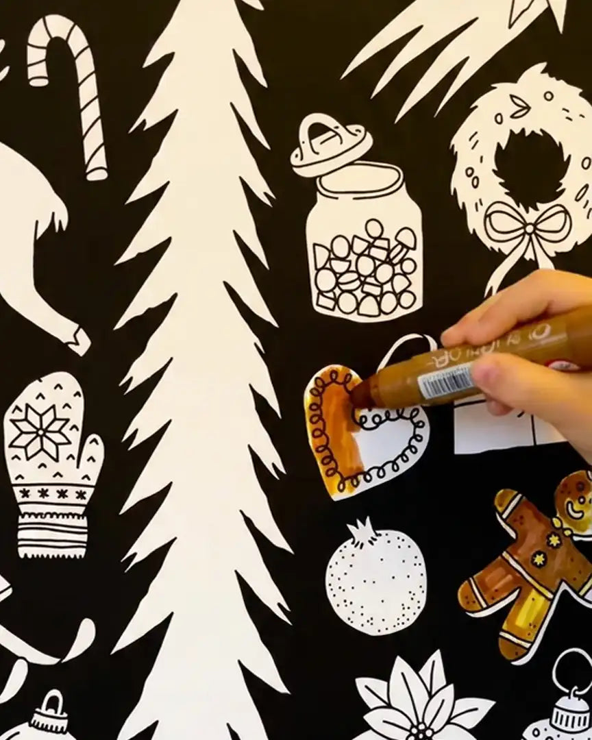 Detalle del Calendario de Adviento Coloreable Cocolitos, donde se aprecia una mano de niño pintando las figuras.